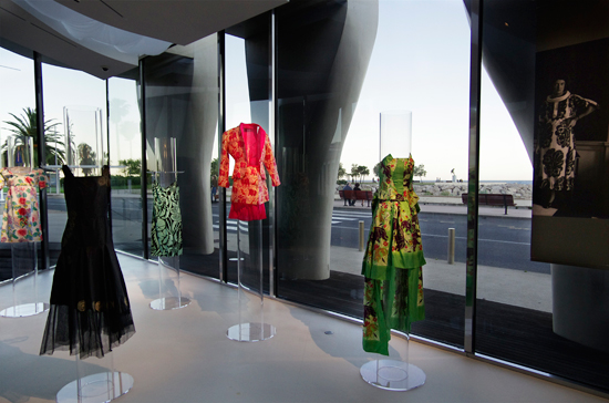 Un assortiment de robes de Paul Poiret devant les murs de verre qui donnent sur la promenade du bord de mer